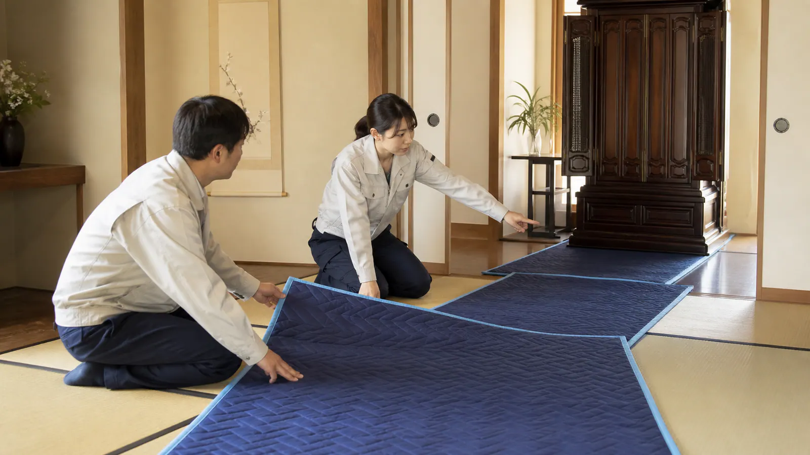 玄関までの経路を養生し大型仏壇を搬出する準備をする作業員