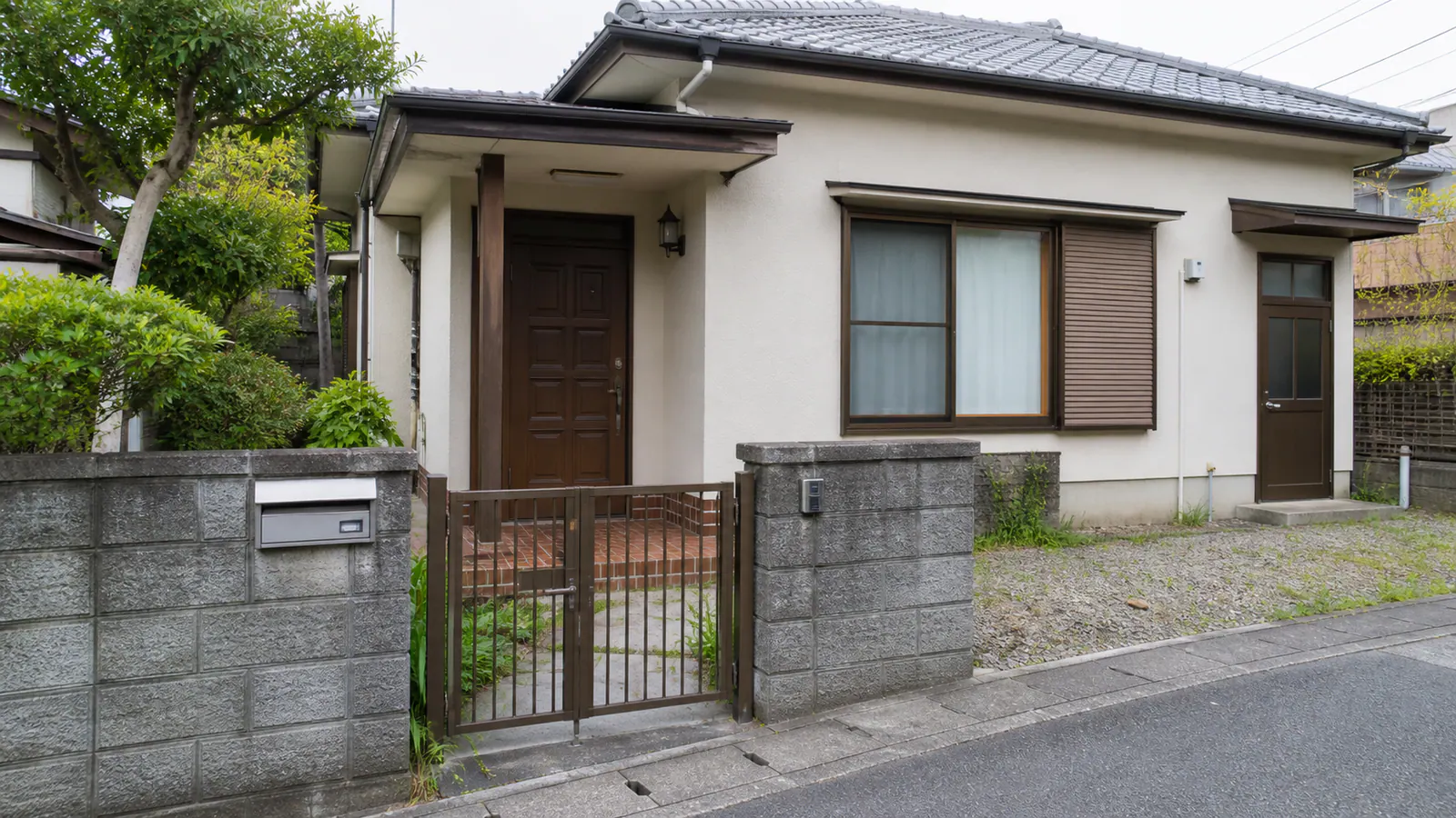 門扉、玄関、勝手口、窓、郵便受けを順に確認できる空き家の外観