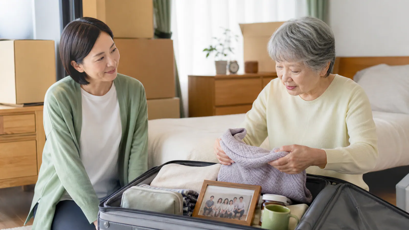 施設へ持っていく写真や衣類を親子で相談しながら箱へ分ける様子